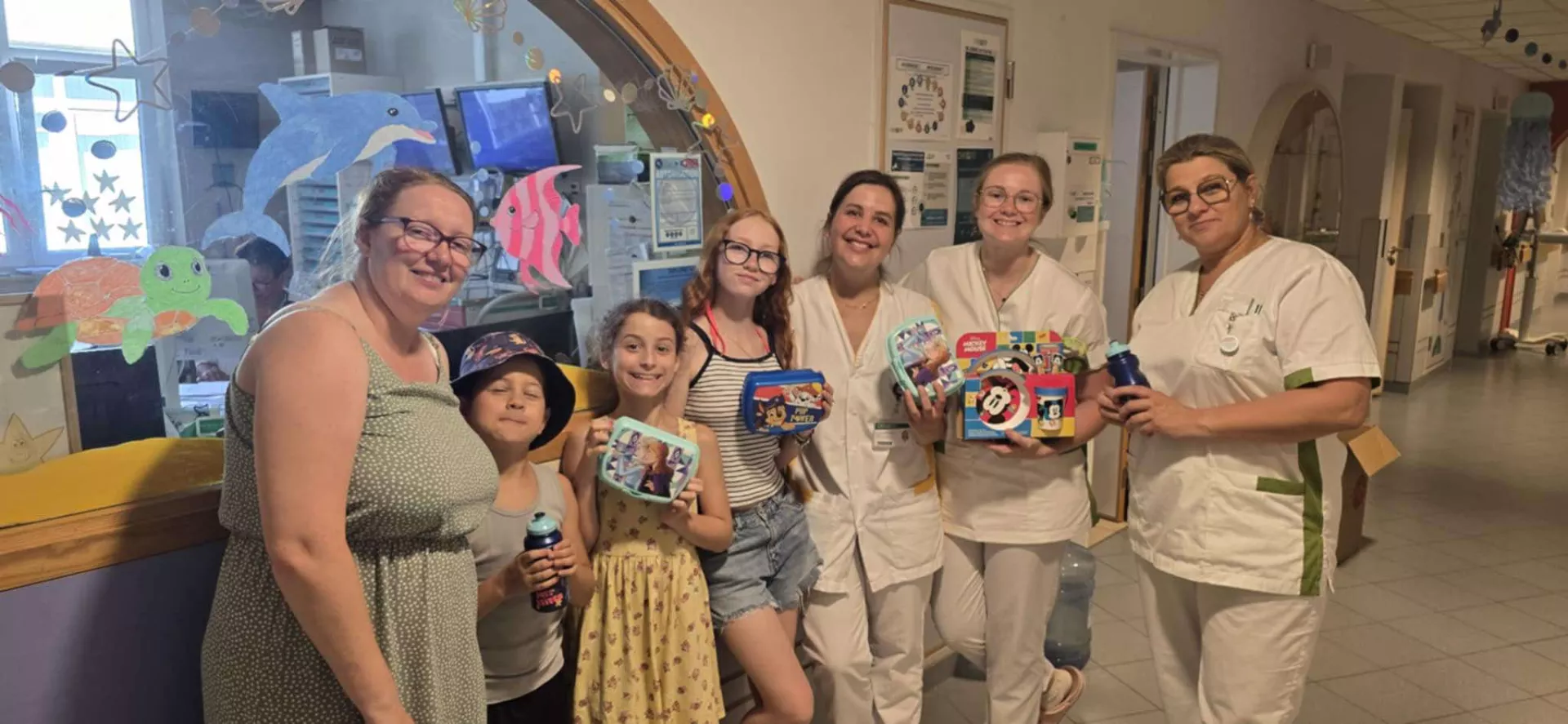 Photo de groupe comprenant des enfants, adultes et personnel du service de pédiatrie. Ils posent avec des gourdes qui ont été offertes par l'asbl Warriors Kids