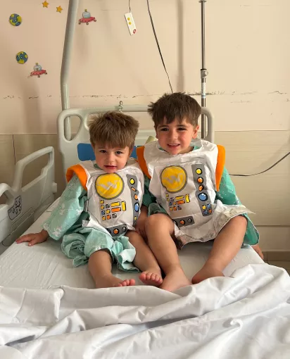 Deux enfants avec une tenue d'astronaute dans un lit d'hôpital dans une chambre de pédiatrie