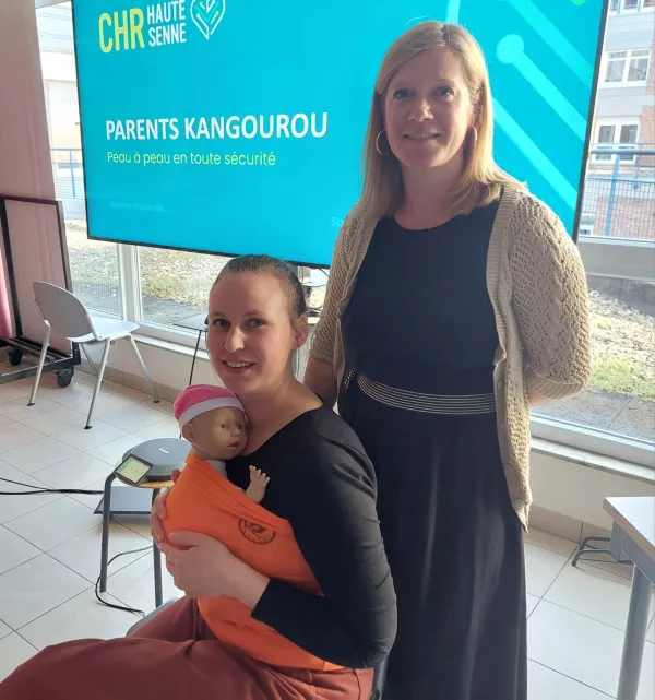 deux femmes avec un porte bébé et un faux bébé