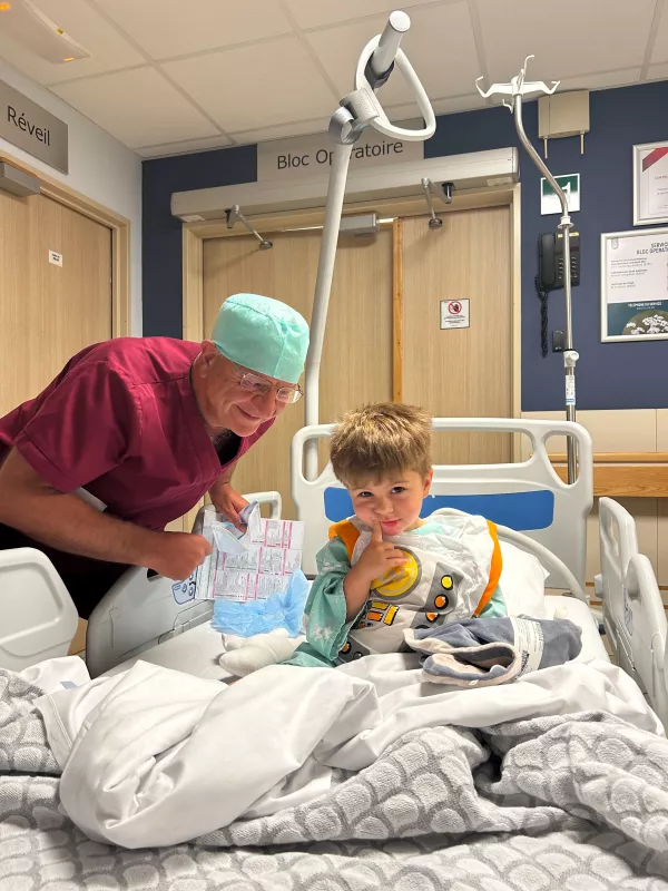 Petit patient dans un lit d'hôpital accompagné d'un anesthésiste, en attendant de rentrer dans le bloc opératoire